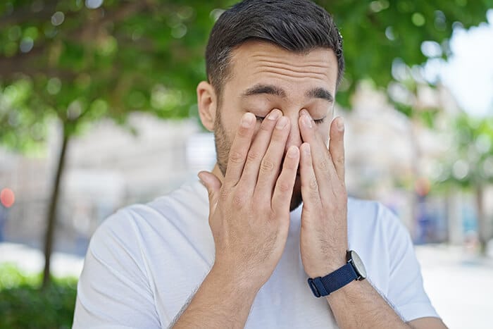 Man rubbing his eyes due to allergies